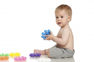 Baby playing with colorful toys on the floor, over white background