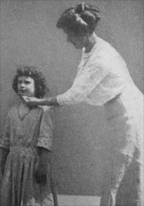 A girl has her head positioning corrected by a school teacher. 1913.